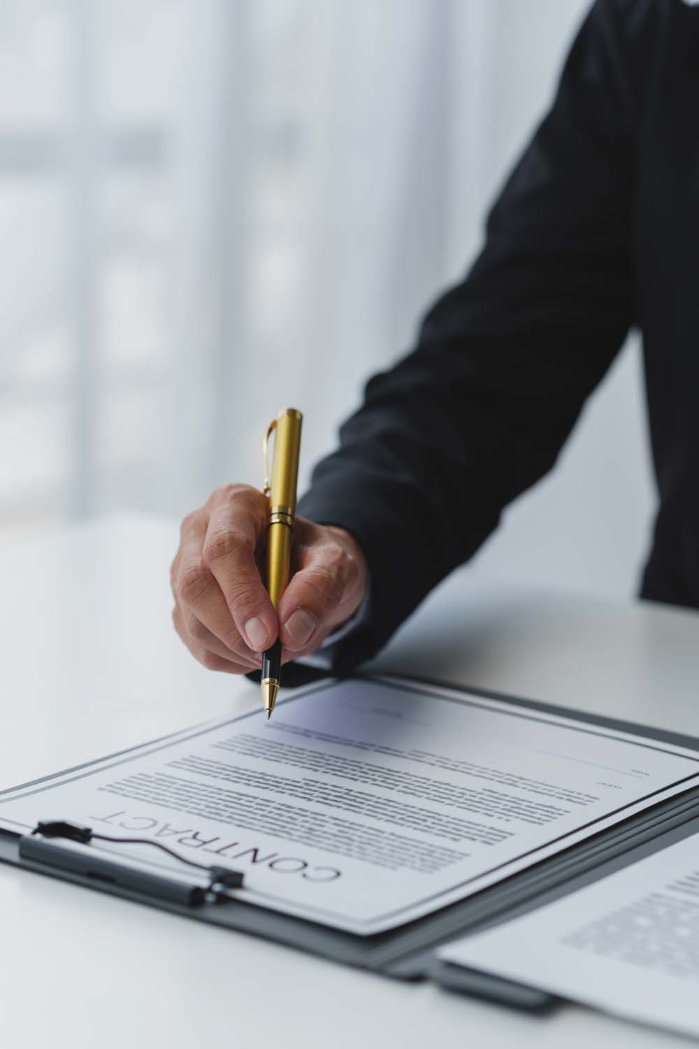 Business professional signing a real estate contract with a gold pen